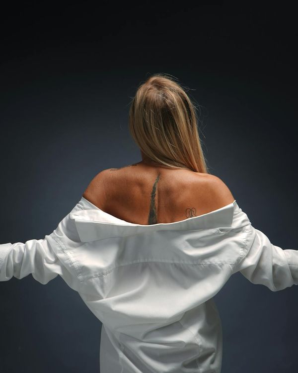 Woman in a peaceful yoga pose against a dark background with pink light.